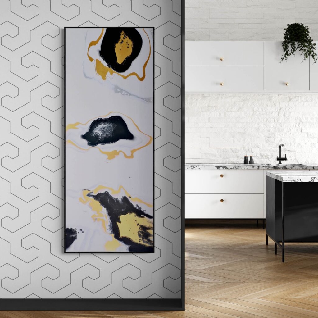 Whisper of Time - 61x153 cm, an abstract painting featuring black, yellow, and white hues, is displayed on a wall adorned with geometric wallpaper; in the background, you can see a modern white kitchen with a sleek black island. Abstract Art by Thanh Lyons